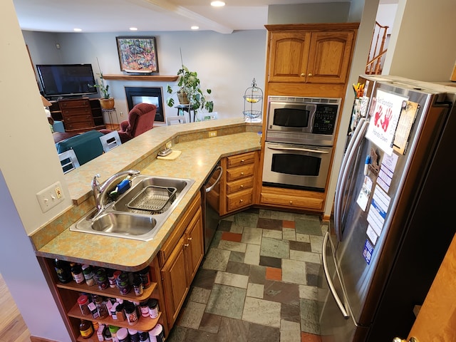 kitchen with a peninsula, light countertops, stainless steel appliances, and a sink