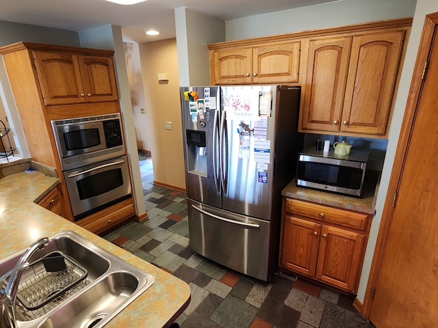 kitchen with a sink, stainless steel appliances, light countertops, and brown cabinets