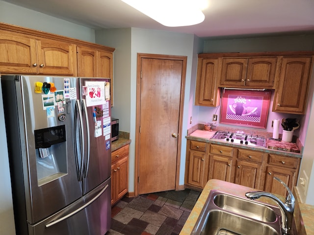 kitchen with appliances with stainless steel finishes, brown cabinets, and a sink