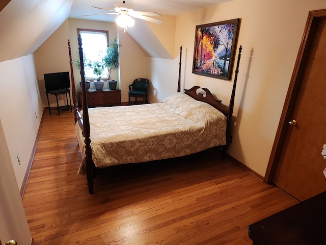 bedroom featuring light wood-type flooring, vaulted ceiling, baseboards, and ceiling fan