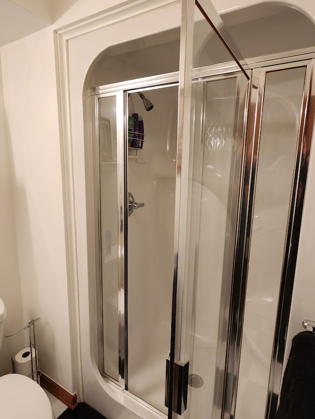 bathroom featuring toilet and a stall shower