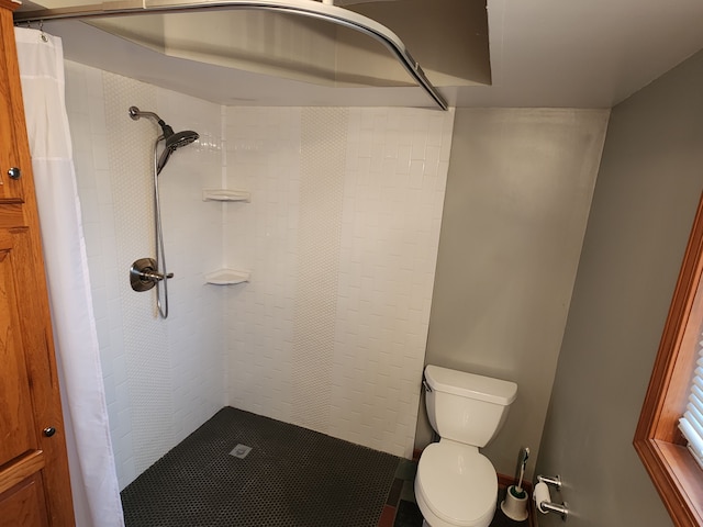 bathroom featuring toilet and tiled shower