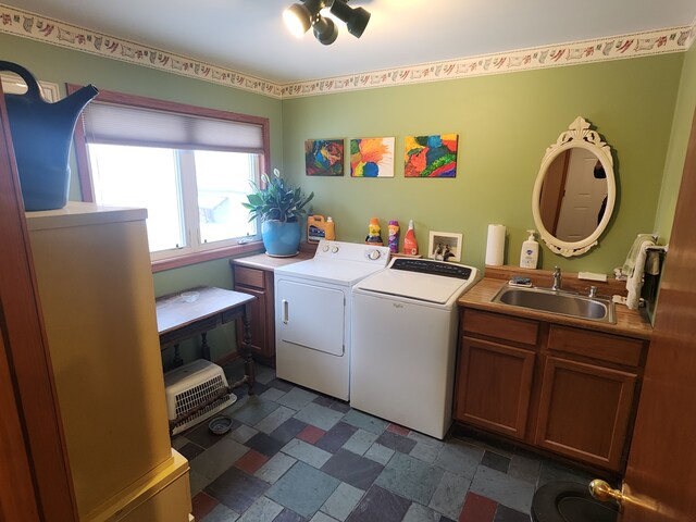 washroom with washing machine and dryer, cabinet space, and a sink