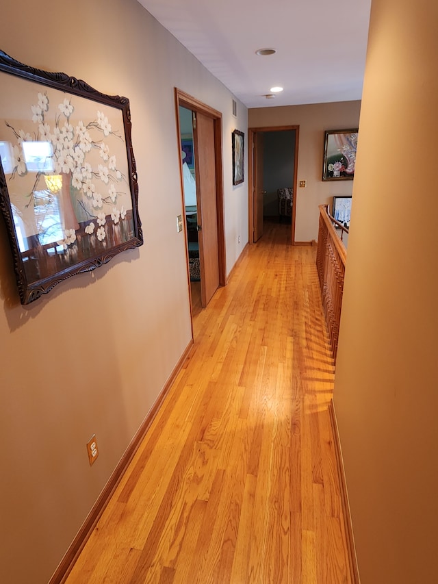 corridor with baseboards and light wood finished floors