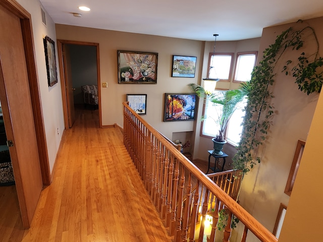 corridor with baseboards, light wood-type flooring, visible vents, and recessed lighting