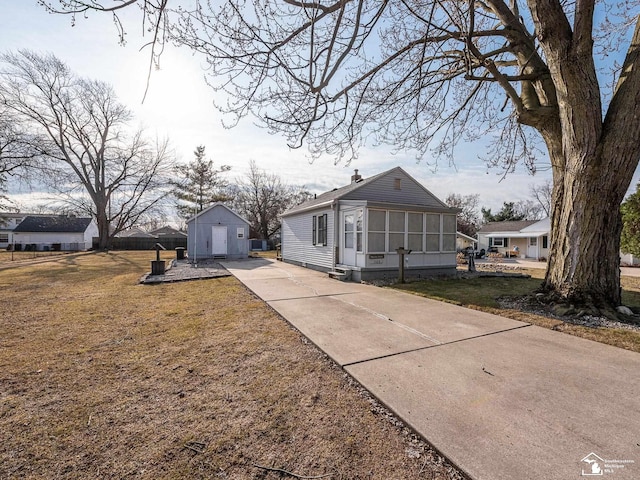 view of front facade featuring an outbuilding, a sunroom, a front lawn, and driveway