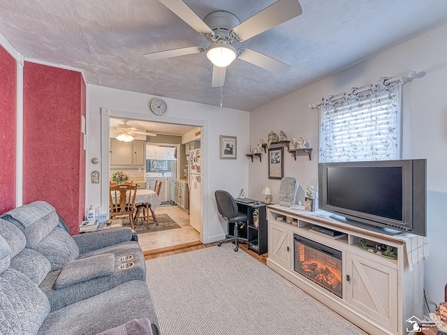 living room featuring wood finished floors, a ceiling fan, and a textured ceiling