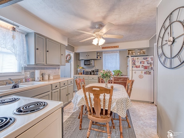 kitchen with a sink, white appliances, ceiling fan, and gray cabinetry