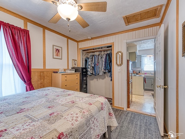 bedroom featuring a ceiling fan, attic access, a closet, a textured ceiling, and crown molding