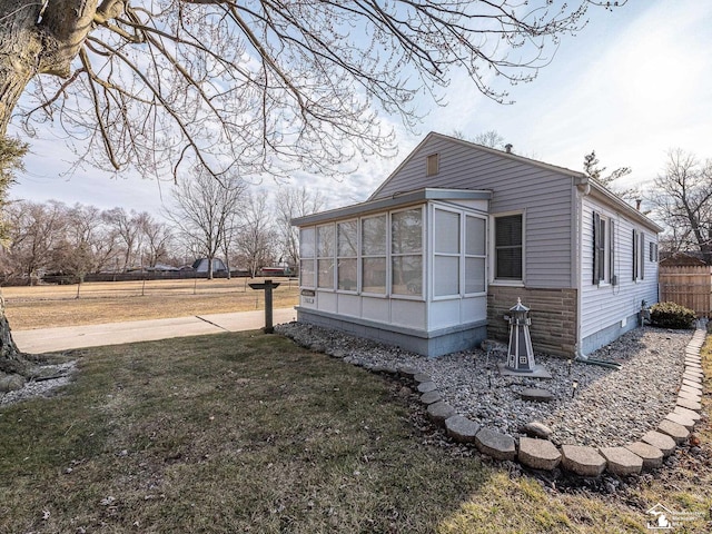 view of property exterior with a sunroom, a yard, and fence