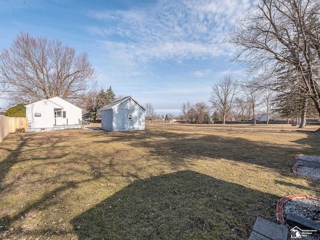 view of yard featuring an outbuilding, a storage unit, and fence