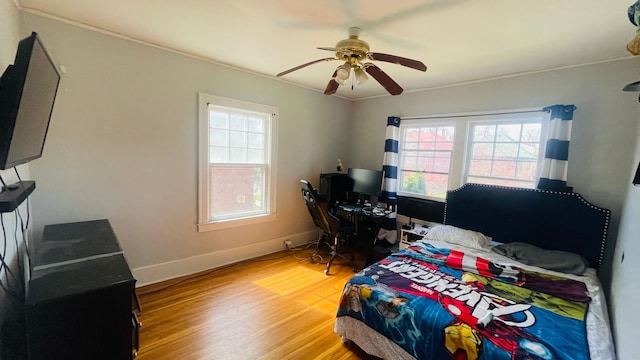 bedroom with light wood finished floors, a ceiling fan, and baseboards