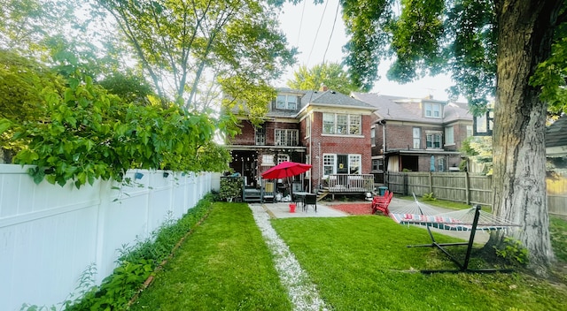 rear view of house featuring brick siding, a patio area, a lawn, and a fenced backyard