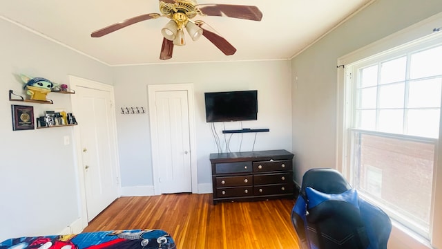 bedroom featuring ceiling fan, wood finished floors, baseboards, and ornamental molding