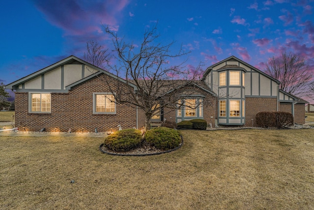 view of front facade with a lawn, brick siding, and stucco siding