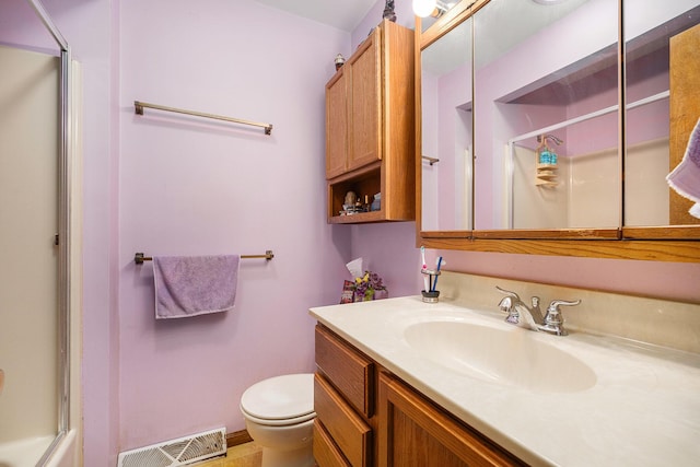 bathroom with vanity, toilet, visible vents, and a shower with door