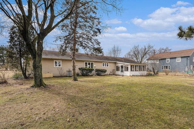 rear view of house with a lawn, central AC, and a sunroom