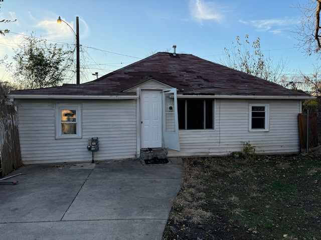 rear view of house featuring a patio area and a shingled roof