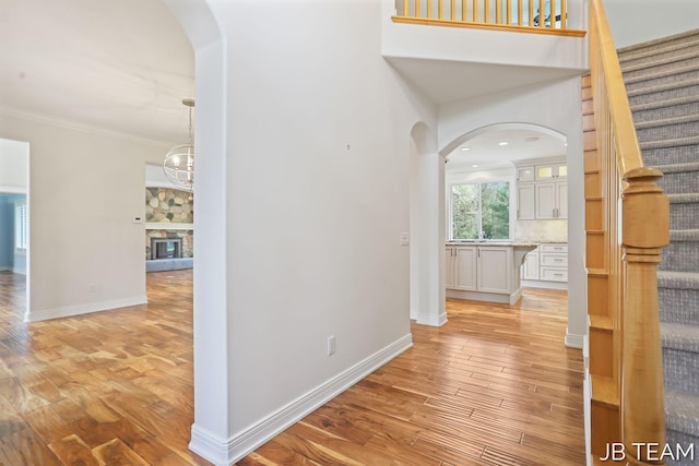 6579 Partridge Ln, Holland, MI 49423 - hall featuring arched walkways, light wood finished floors, baseboards, stairway, and ornamental molding