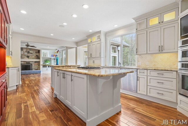 6579 Partridge Ln, Holland, MI 49423 - kitchen featuring crown molding, open floor plan, dark wood finished floors, a kitchen island, and appliances with stainless steel finishes