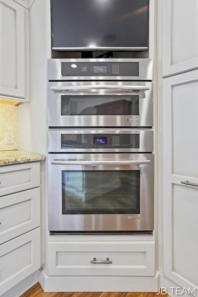 6579 Partridge Ln, Holland, MI 49423 - kitchen view of stainless steel double oven, decorative backsplash, and white cabinetry