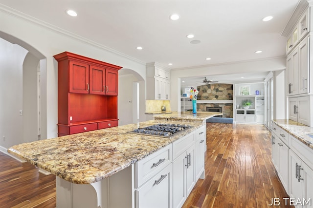 6579 Partridge Ln, Holland, MI 49423 - kitchen with stainless steel gas cooktop, open floor plan, dark wood-style flooring, arched walkways, and crown molding