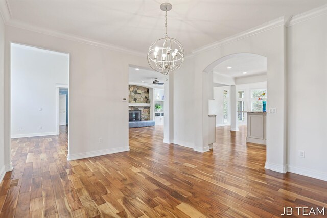 6579 Partridge Ln, Holland, MI 49423 - unfurnished dining area featuring arched walkways, a chandelier, wood finished floors, a ceiling fan, and ornamental molding