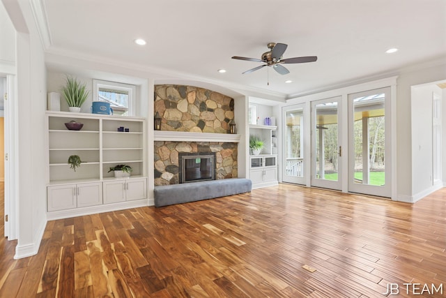 6579 Partridge Ln, Holland, MI 49423 - unfurnished living room with crown molding, wood finished floors, a stone fireplace, a ceiling fan, and recessed lighting