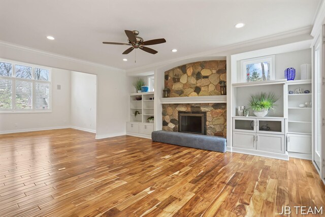 6579 Partridge Ln, Holland, MI 49423 - unfurnished living room with ornamental molding, light wood finished floors, a stone fireplace, ceiling fan, and recessed lighting