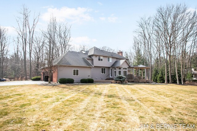 6579 Partridge Ln, Holland, MI 49423 - rear view of property with a chimney, a yard, driveway, and a deck