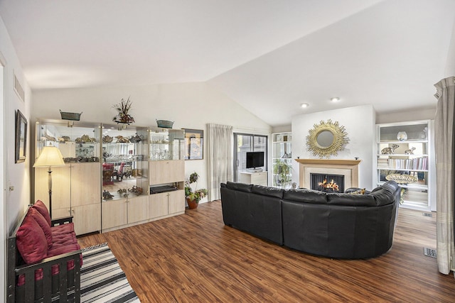 23930 Greenglen Ct, Franklin, MI 48025 - living area with visible vents, a warm lit fireplace, lofted ceiling, and wood finished floors