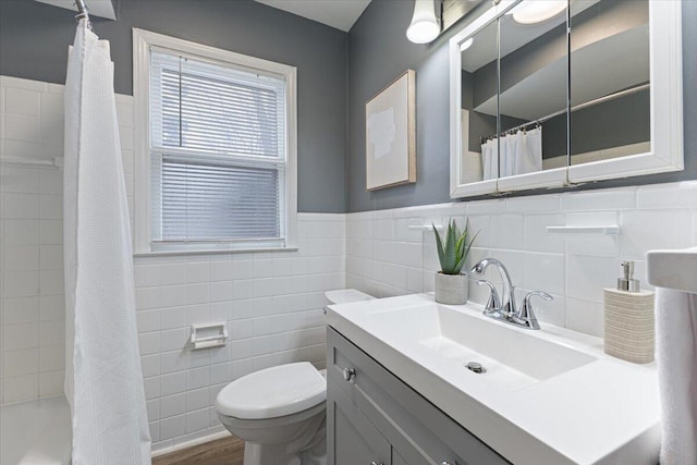 full bath with curtained shower, toilet, tile walls, and a wainscoted wall