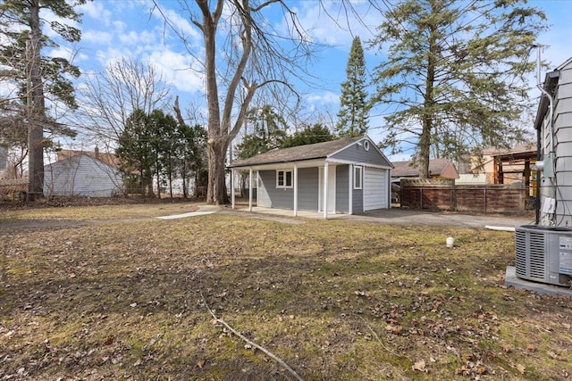 view of yard featuring an outbuilding, cooling unit, fence, and a detached garage