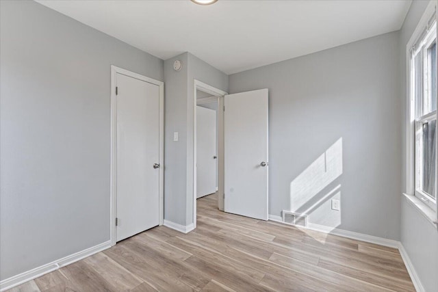 unfurnished room with light wood-type flooring, visible vents, and baseboards
