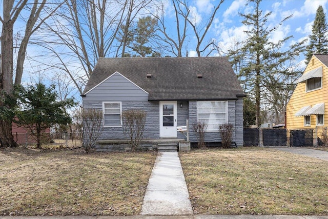 view of front facade featuring roof with shingles, a front lawn, and fence