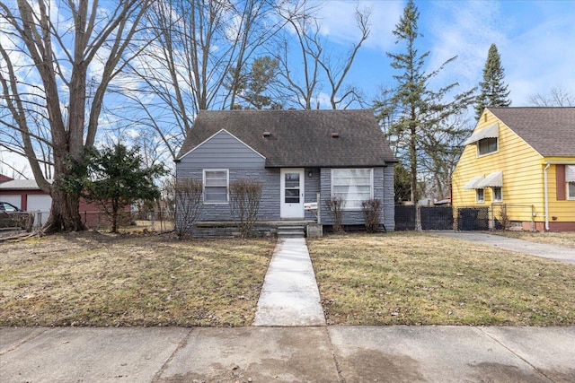 view of front of house featuring a shingled roof, a front lawn, and fence