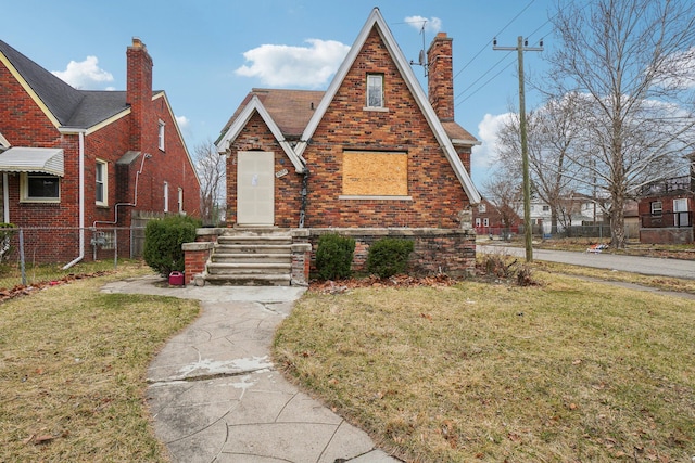 tudor house with a front lawn, fence, and a chimney