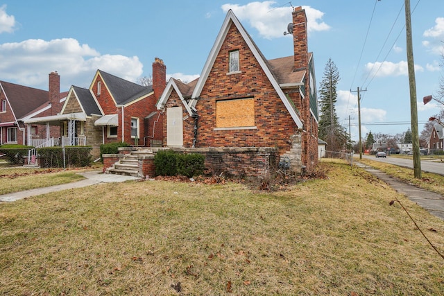 tudor house featuring brick siding, stone siding, and a front yard