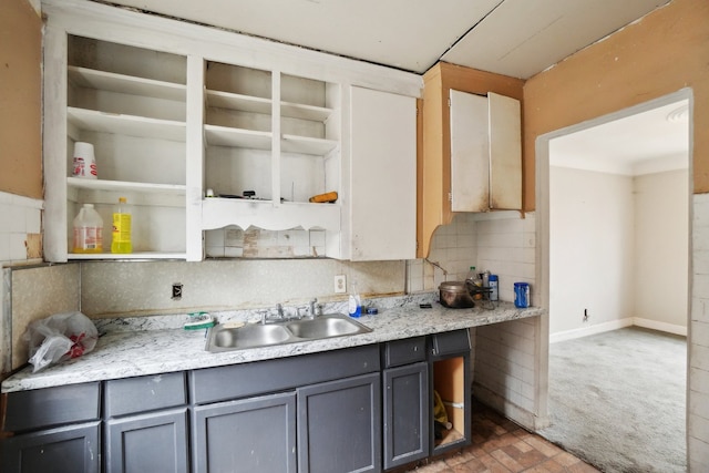 kitchen featuring open shelves, gray cabinetry, a sink, light countertops, and backsplash