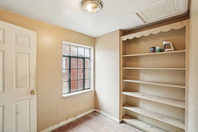 interior space featuring baseboards, attic access, and hardwood / wood-style flooring