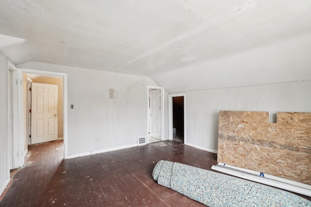 unfurnished bedroom with hardwood / wood-style flooring, baseboards, visible vents, and vaulted ceiling