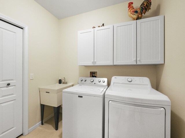 washroom featuring cabinet space, washing machine and dryer, and baseboards