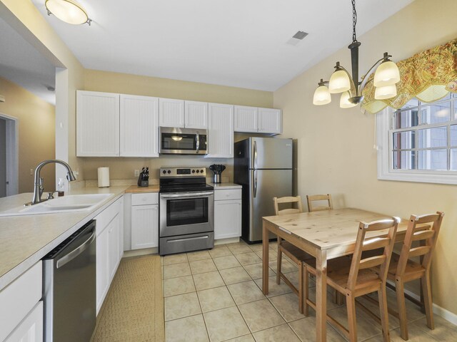kitchen featuring light countertops, light tile patterned floors, white cabinets, stainless steel appliances, and a sink