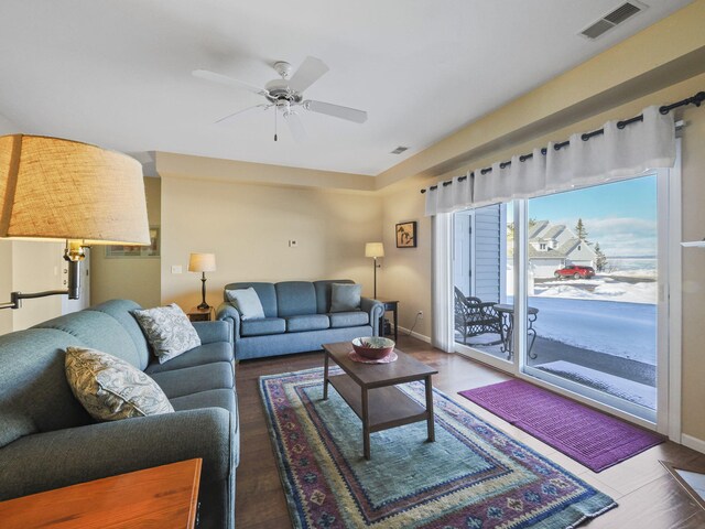 living area featuring visible vents, baseboards, a ceiling fan, and wood finished floors