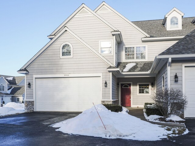 view of front of property with driveway, a shingled roof, and a garage