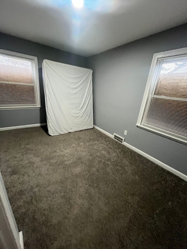 unfurnished room with carpet flooring, plenty of natural light, and baseboards