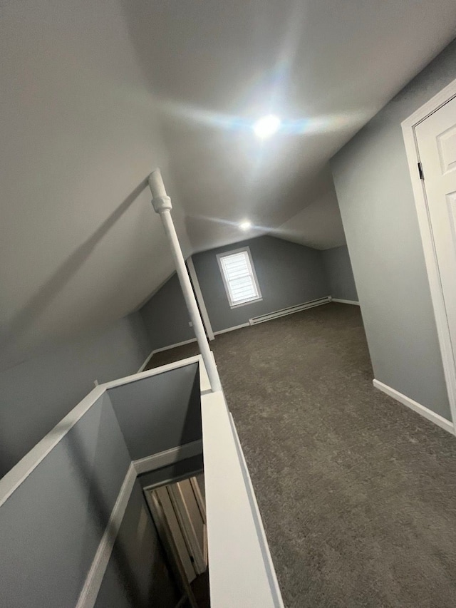 additional living space featuring dark colored carpet, baseboards, and lofted ceiling