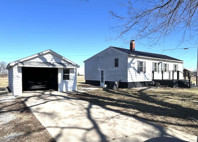view of side of property with an outbuilding, driveway, a garage, central AC unit, and a chimney