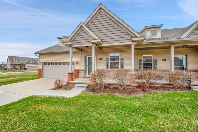 259 Victoria Dr, Dexter, MI 48130 - craftsman-style house featuring an attached garage, a front lawn, a shingled roof, a porch, and driveway