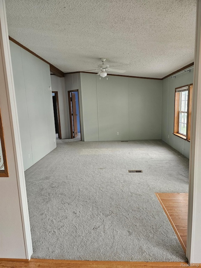 73 Grey Fox Ct, Grand Blanc, MI 48439 - spare room featuring carpet floors, a ceiling fan, a textured ceiling, ornamental molding, and a decorative wall